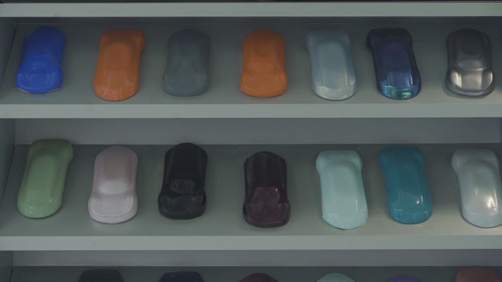 Modèles réduits de voitures avec film de protection PPF coloré, présentés sur une étagère d'exposition