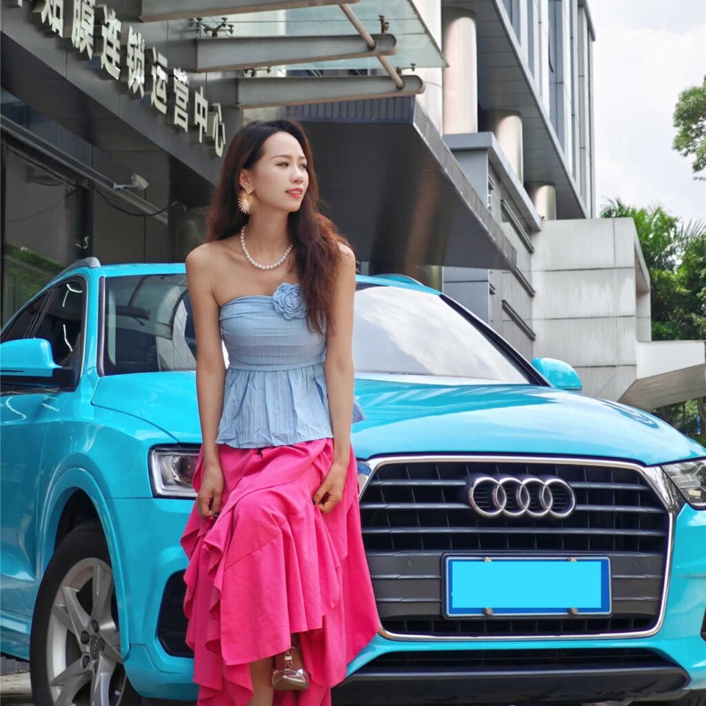 Professional showgirl posing next to luxury black sedan
