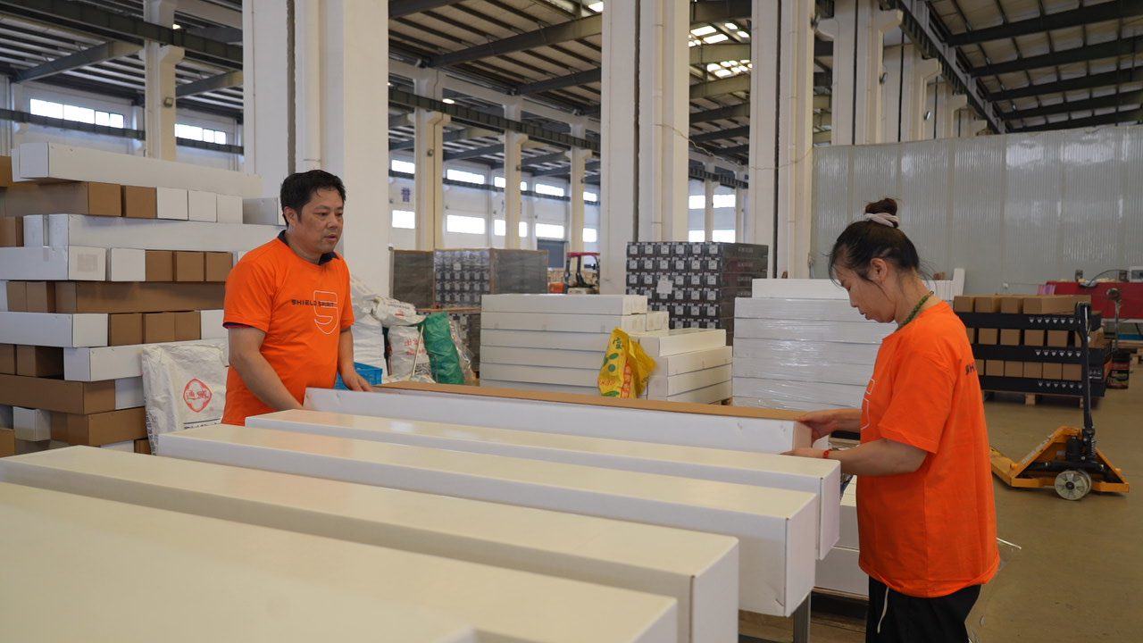Worker stacking boxed rolls at PPF factory warehouse