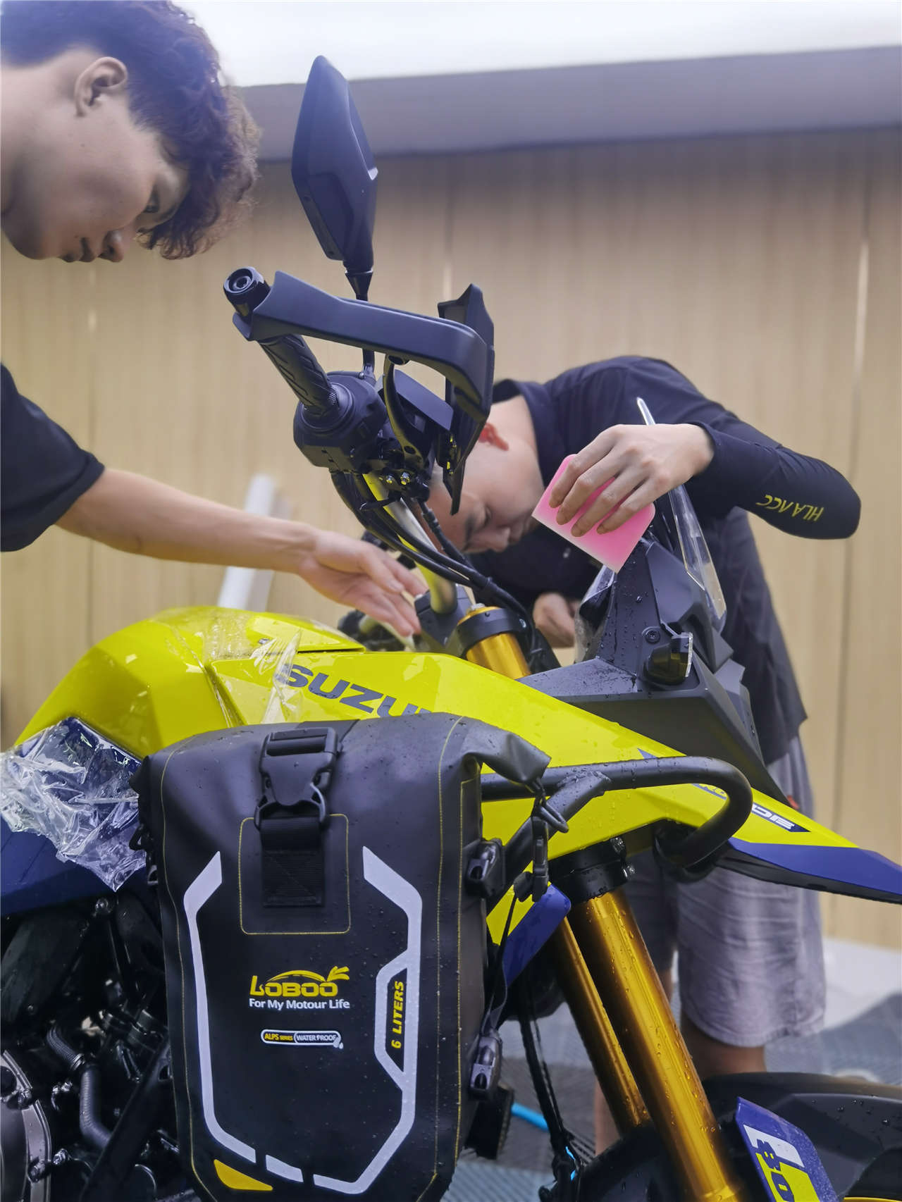 Suzuki motorcycle full side view with SHIELD SPIRIT PCU PPF partially applied - showroom lighting reveals gloss finish on fairing panels and fuel tank