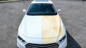 Realistic comparison of a white car hood where fresh clear paint protection film keeps the paint pristine, while the right side shows heavily yellowed aged film over white paint.
