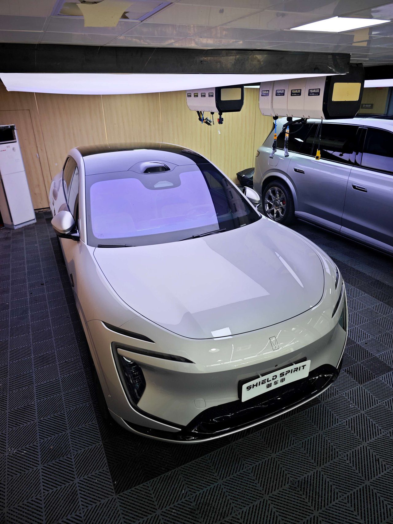 Wide view of installation workshop with multiple vehicles including SUV receiving full PPF coverage