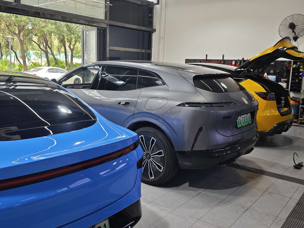 Technicians installing paint protection film on a luxury vehicle inside the YuCheJia Foshan flagship store