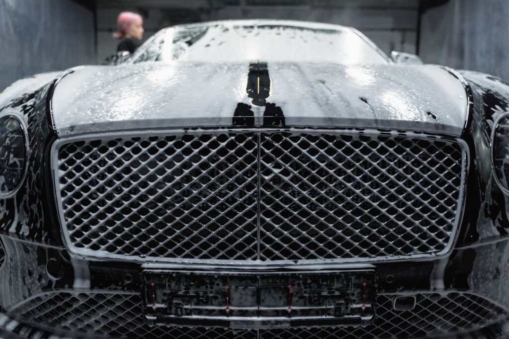 Mastering the First Impression: Your intriguing post title goes here A close-up of a luxurious black car being cleaned with foamy soap at a carwash.