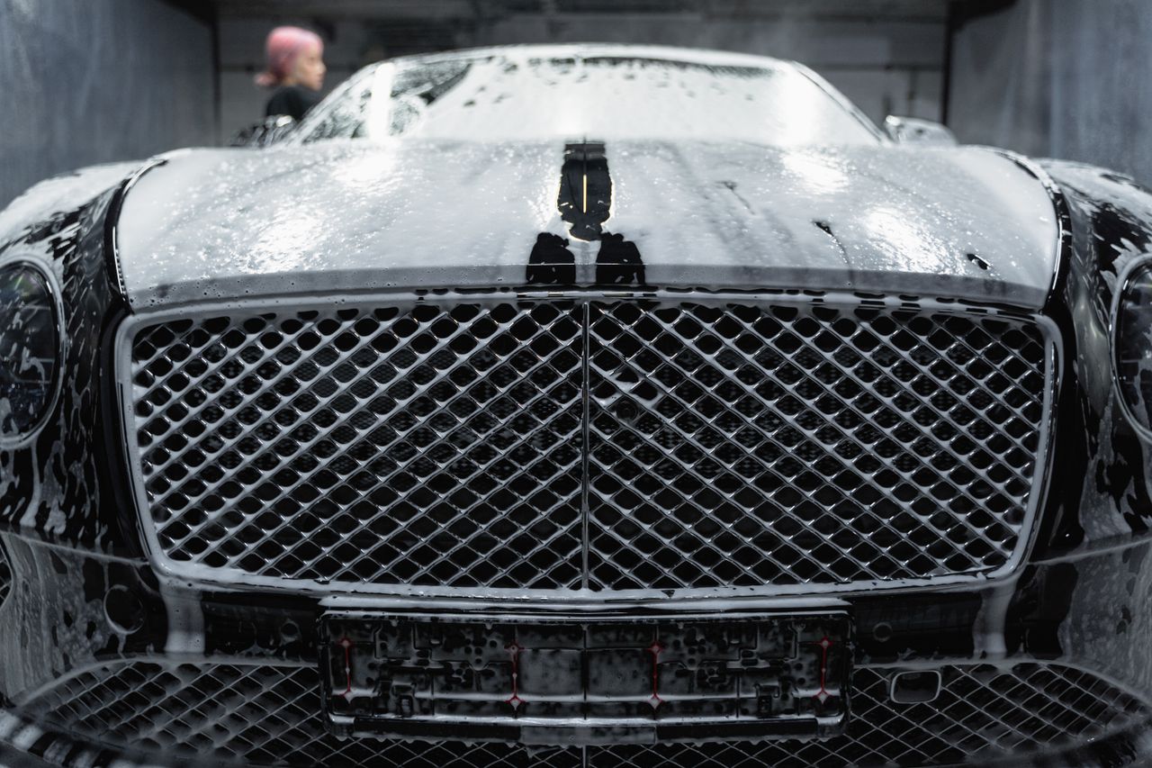 Mastering the First Impression: Your intriguing post title goes here A close-up of a luxurious black car being cleaned with foamy soap at a carwash.