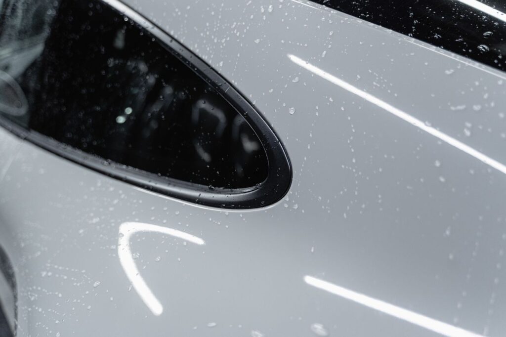 The Art of Drawing Readers In: Your attractive post title goes here A detailed view of a white car with water droplets after a wash, showcasing its shine.